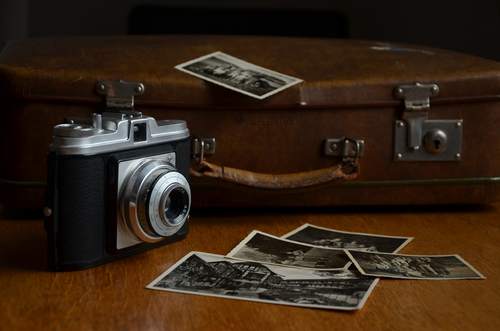 Oude koffer met een ouderwetse camera en een aantal zwart-foto's. Bron Pixabay.