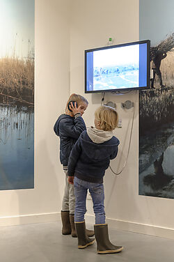 Twee kinderen kijken en luisteren naar video in Biesbosch MuseumEiland. Fotograaf Ben Nienhuis. Erfgoed Brabant.