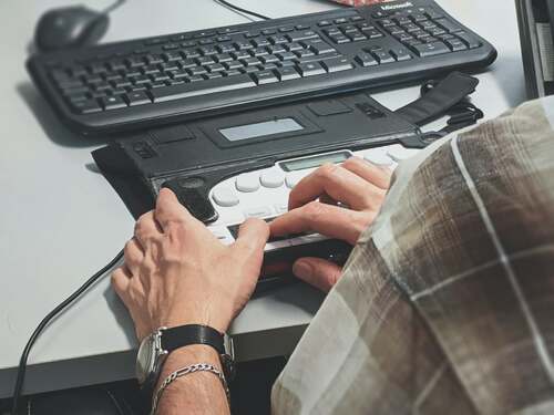 Persoon leest braille via screenreader aan zijn computer. Foto Sigmund. Bron Unsplash