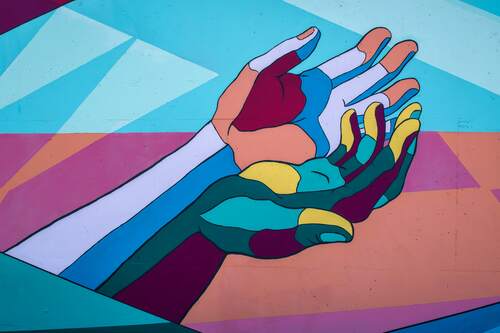 Muurschildering van gekleurde handen. Fotograaf: Tim Mossholder. Bron: Unsplash.