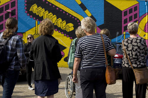 Groep mensen staat op parkeerplaats tijdens rondleiding Blind Walls Gallery tijdens Erfgoedontmoeting 2018. Fotograaf Ingeborg Schuster. Bron Erfgoed Brabant.