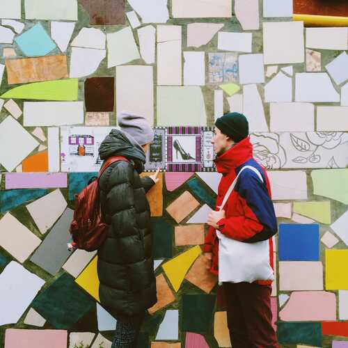 Twee mensen praten met elkaar over muurkunst. Bron Reshot.