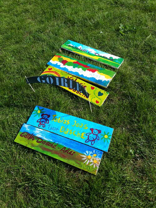 Vijf naambordjes van het herdenkingsproject Namen en Nummers Tilburg liggen in het gras. Foto Rianne Walet. Bron Erfgoed Brabant