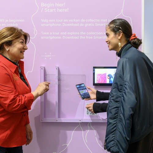 Vrijwilliger in het Van Abbemuseum legt een app uit aan een bezoeker. Fotograaf Ben Nienhuis. Bron Erfgoedvrijwilliger.