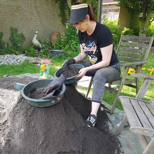 Vrijwilliger zeeft opgegraven zand in tuin in Boxtel. CARE. Foto Erfgoed Brabant.